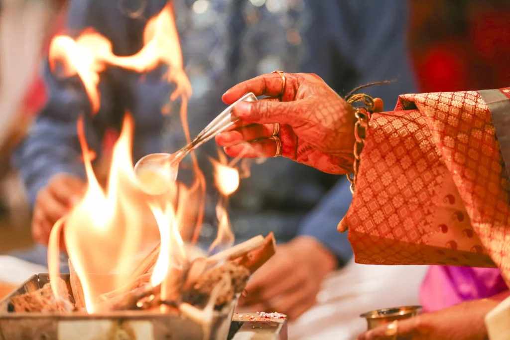 Putting spoon in fire during Indian wedding tradition. 