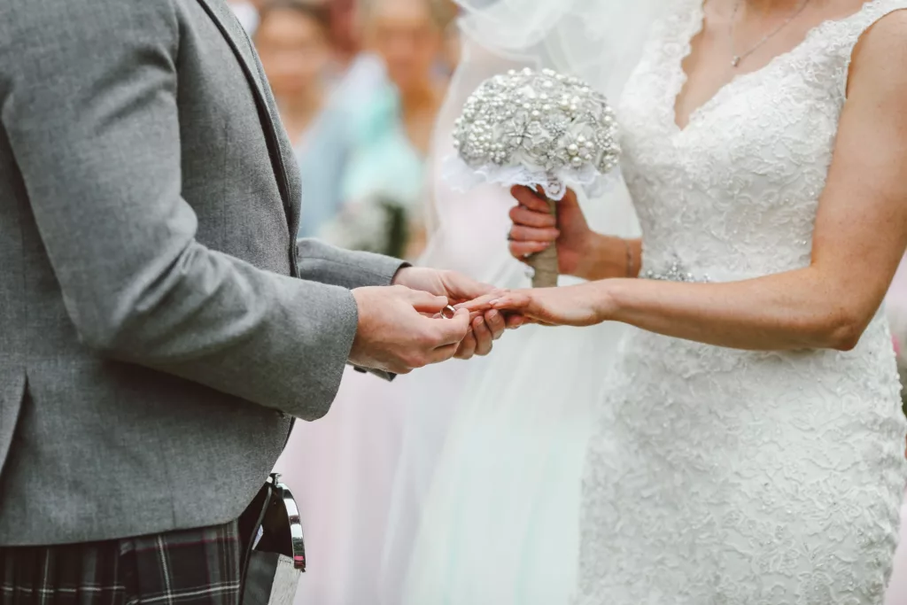 Groom putting ring on bride